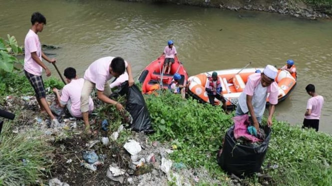 Pemuda dan pemudi membersihkan sampah di sungai